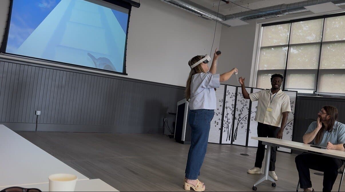A participant works through a VR experience while a Bubbler facilitator guides the session and others watch the headset view on a screen