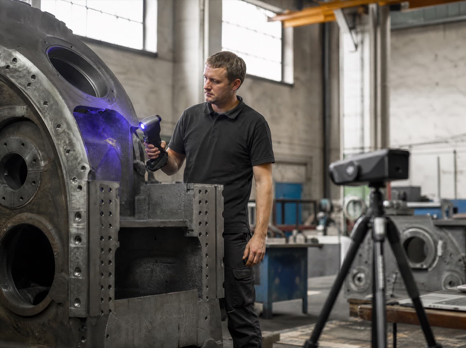 A technician 3D scanning a large industrial machine to reconstruct it inside a simulation